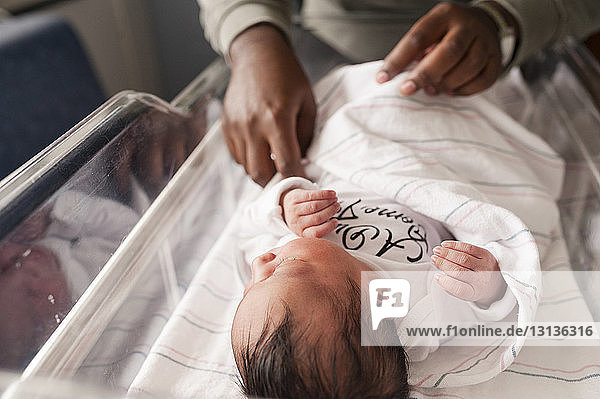 Beschnittenes Bild einer Person  die die Decke eines Neugeborenen anpasst