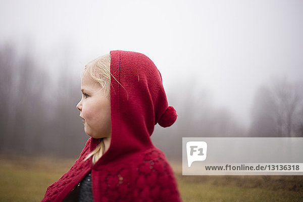 Close-up of girl standing on field during foggy weather
