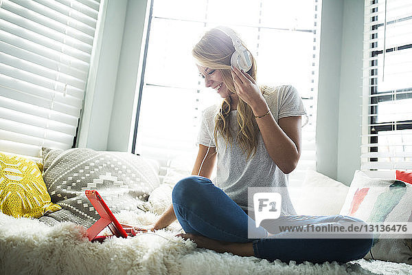 Frau hört Musik  während sie auf einem Fensterplatz in einer Nische sitzt