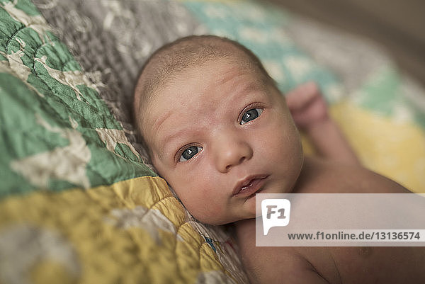 Nahaufnahme-Porträt eines neugeborenen Jungen  der zu Hause auf dem Bett liegt