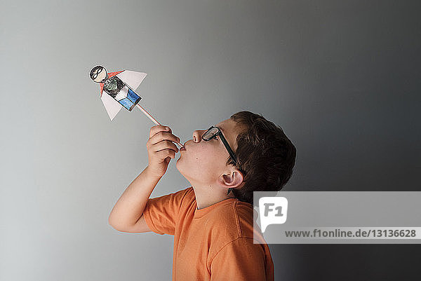 Seitenansicht eines Jungen  der zu Hause mit einem Superhelden-Spielzeug an der Wand spielt