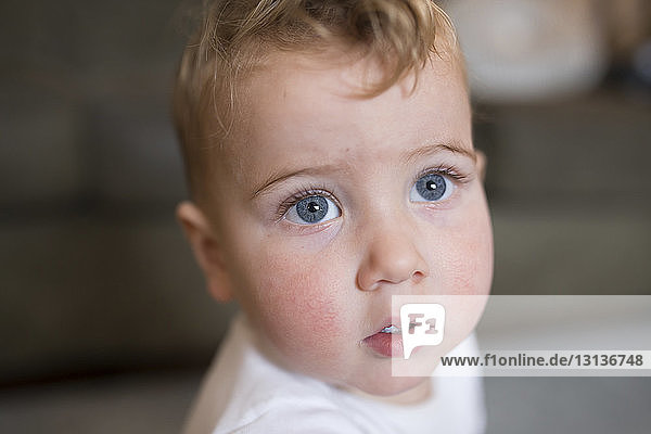 Close-up of cute baby boy with gray eyes looking away at home
