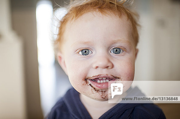 Porträt eines süßen kleinen Jungen  dem zu Hause das Essen um den Mund herumgeworfen wird