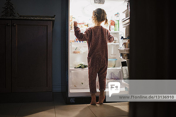 Rückansicht eines Mädchens  das zu Hause am Kühlschrank steht