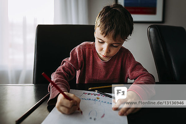 Zeichnung eines Jungen mit Buntstift auf Papier zu Hause