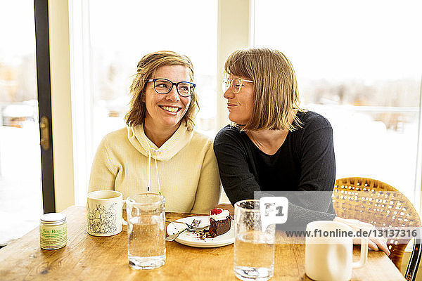 Sisters talking while sitting by table at home