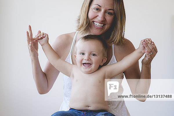 Portrait of cheerful shirtless son and mother against white background