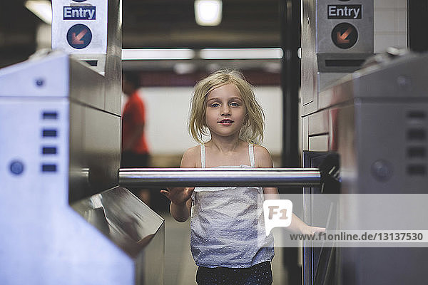 Portrait of girl standing at turnstile in railroad station