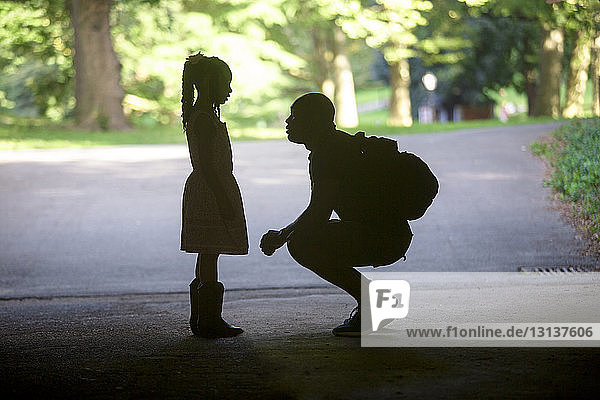 Vater kauert neben der Tochter auf der Straße im Park