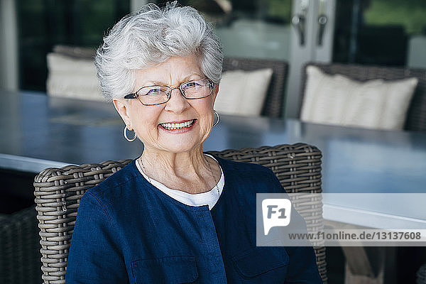 Porträt einer lächelnden älteren Frau  die auf der Veranda sitzt
