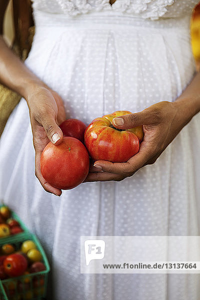 Midsection of woman holding fresh tomatoes at market