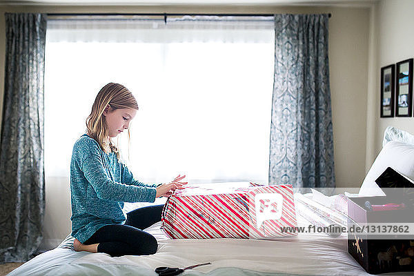 Seitenansicht eines Geschenkkartons für Mädchen  die auf dem Bett knien