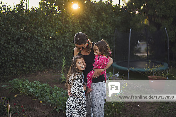 Mutter mit Töchtern bei Sonnenuntergang im Hof stehend