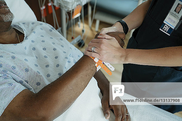 Nahaufnahme einer Krankenschwester  die einen älteren Patienten auf der Krankenhausstation tröstet