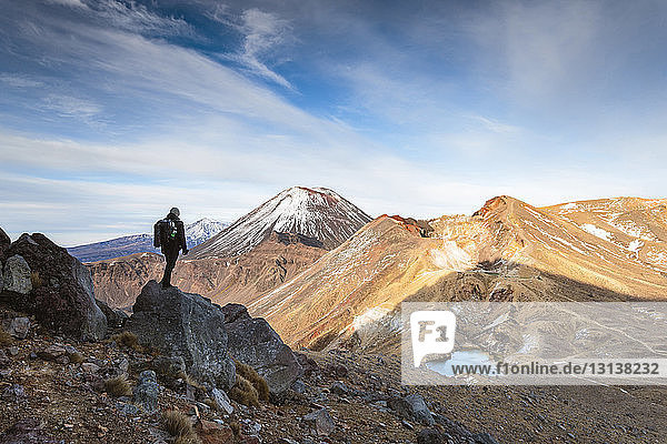 Wanderer betrachtet den Berg Ngauruhoe bei bewölktem Himmel
