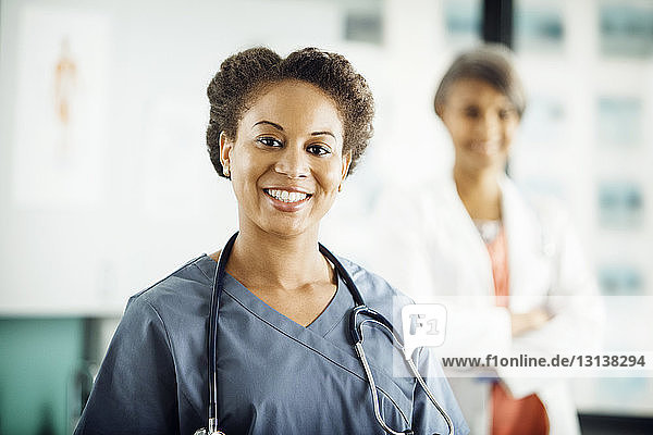 Portrait of happy female doctor with colleague standing in background