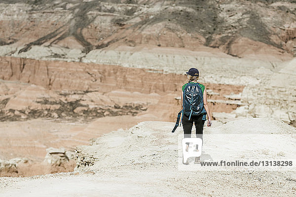 Rückansicht einer Wanderin mit Rucksack beim Wandern in der Wüste