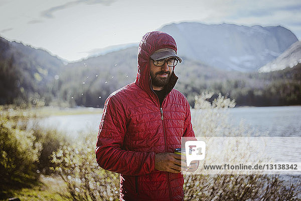 Wanderer mit Kapuze  der eine Getränkedose hält  während er am See im Grand-Teton-Nationalpark steht