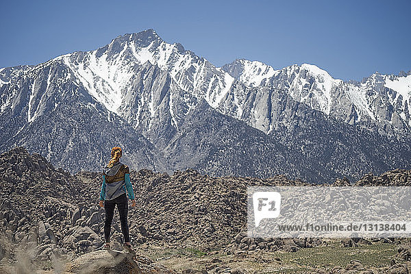 Rear view of female hiker looking at Alabama Hills while standing on rocks