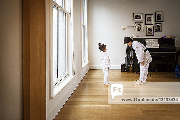 Siblings practicing karate in brightly lit home
