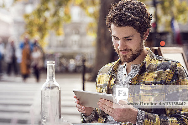 Mann benutzt Tablet-Computer im Straßencafé