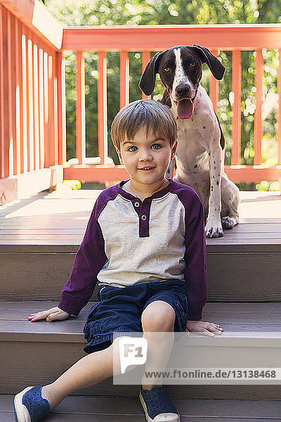 Portrait of boy sitting on steps by dog