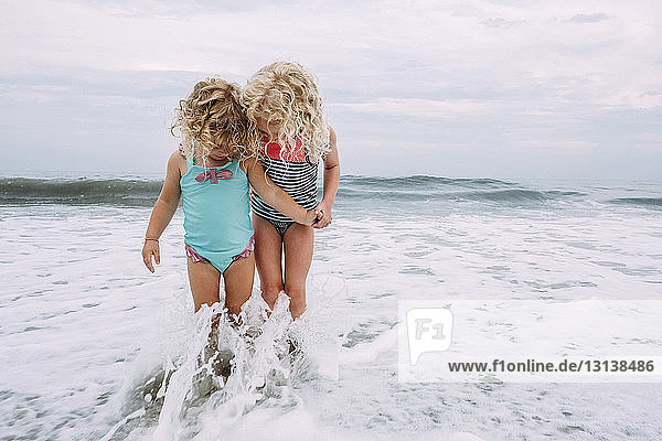 Schwestern spielen in Wellen am Cape May Beach gegen Himmel und Meer