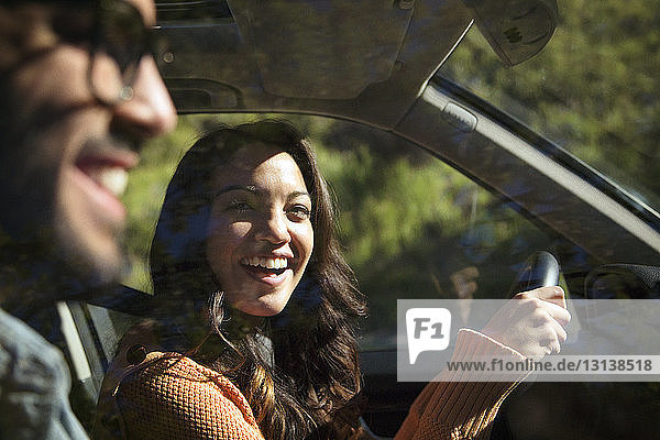 Lächelndes Paar fährt an einem sonnigen Tag im Auto