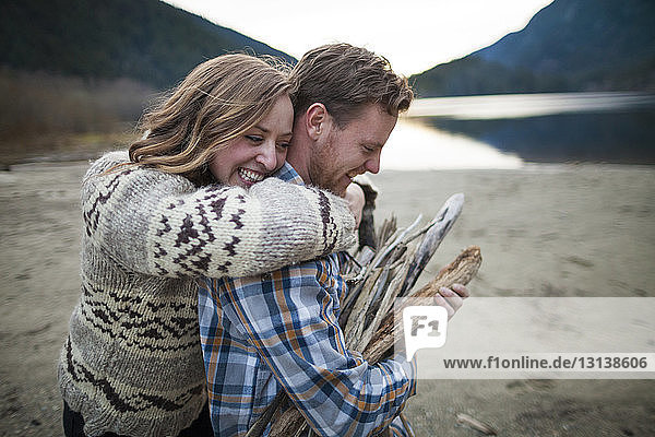Cheerful girlfriend embracing boyfriend carrying firewood at Silver Lake Provincial Park