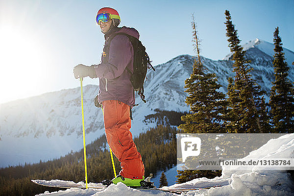 Skier looking away while standing on snow covered mountain