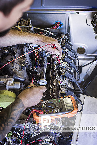 Hochwinkelansicht eines Mechanikers bei der Untersuchung eines Automotors in einer Autowerkstatt