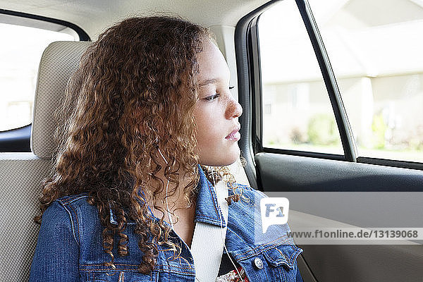 Teenager looking through window while listening music in car