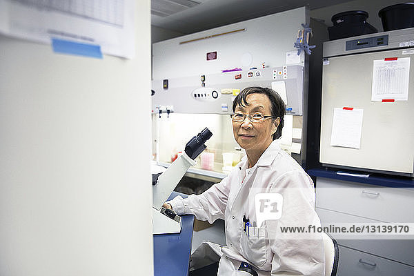 Porträt einer leitenden Wissenschaftlerin mit Mikroskop im Labor