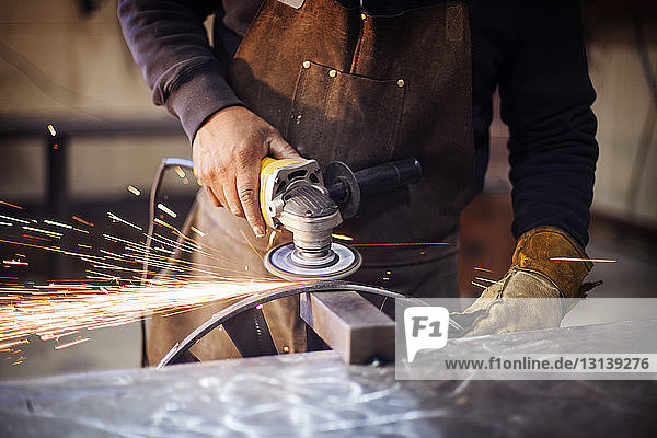 Handwerker mit Kreissäge beim Polieren von Metall in der Fabrik