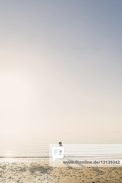 Seitenansicht eines Jungen mit Schwimmweste  der bei nebligem Wetter im Meer läuft