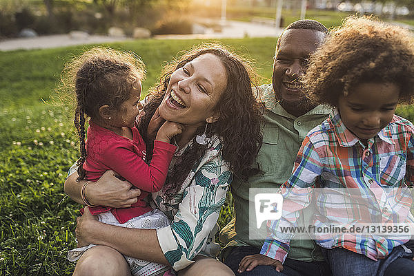 Happy family on grassy field at park during sunset