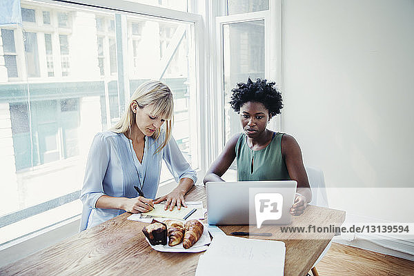 Businesswomen working at conference table in creative office