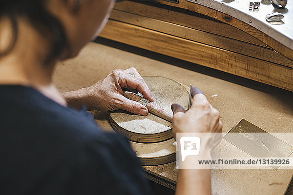 Hochwinkelansicht eines Messrings einer Handwerkerin auf einem Holztisch in der Werkstatt