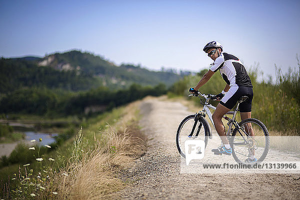 Portrait of cyclist with bicycle on dirt road