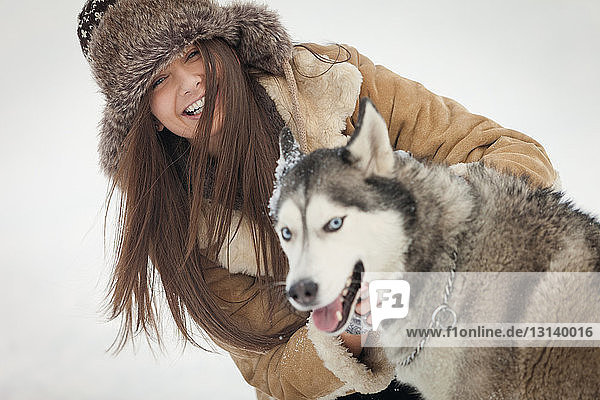 Porträt einer glücklichen Frau mit Siberian Husky im Winter