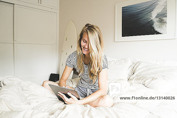 Happy woman using laptop computer on bed at home