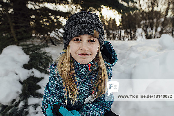 Portrait of girl sitting on snow field