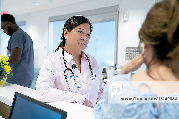 Doctor looking at female colleague with male coworker in background