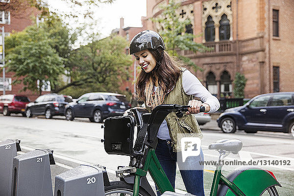 Lächelnde Frau entfernt Fahrrad vom Gepäckträger auf dem Parkplatz