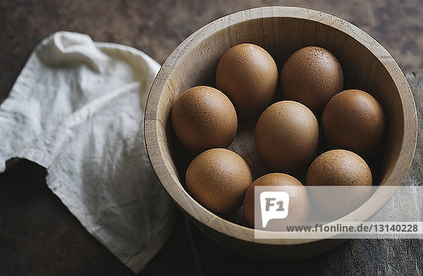Hochwinkelansicht von braunen Eiern in Schale mit Serviette auf Holztisch