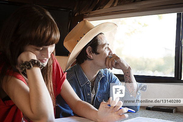 Nachdenklicher Mann sitzt mit Frau zusammen  während er im Wohnmobil reist