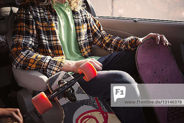 Mittendrin sitzender Mann im Auto mit Skateboards