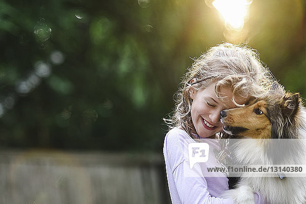 Glückliches Mädchen spielt mit Hund im Park