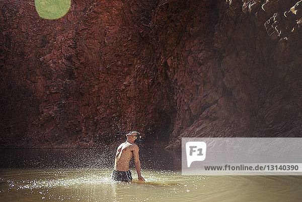Mann ohne Hemd steht und schreit im See am Berg