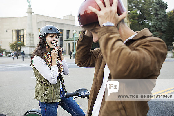 Paar trägt Fahrradhelme  während es auf der Straße in der Stadt steht